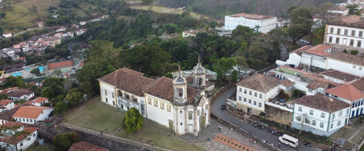 A town with a prominent church, surrounded by lush green hills and residential buildings.