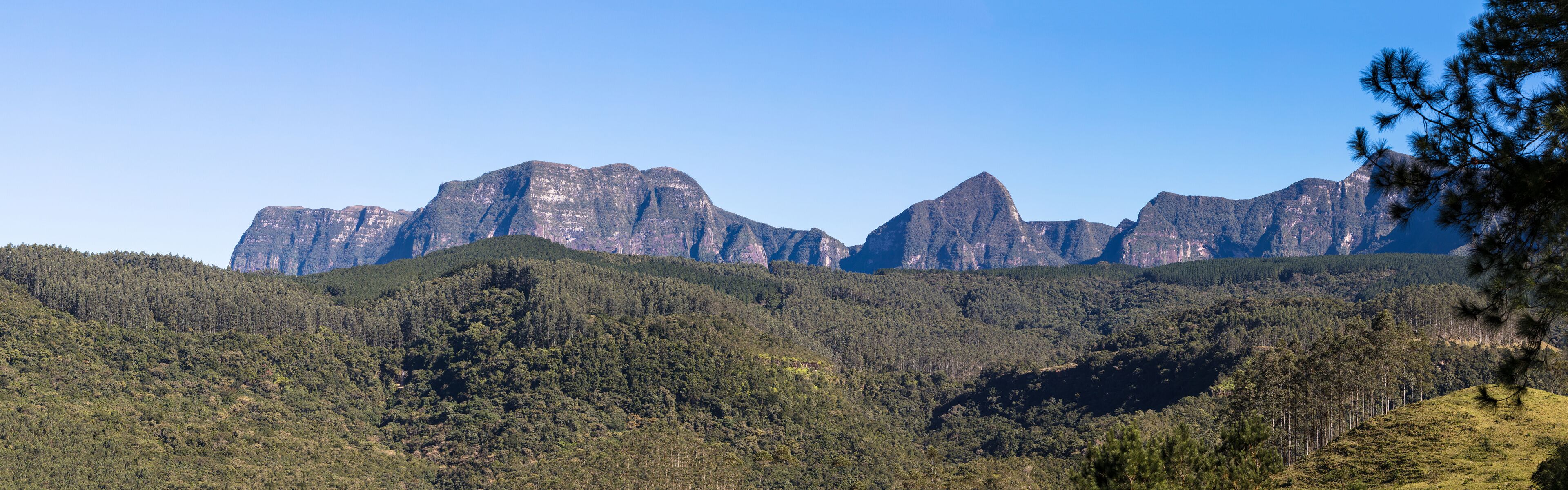 A mountainous landscape with dense forest and prominent peaks.