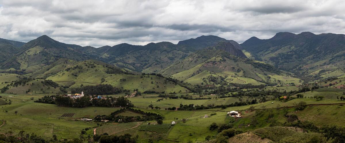A valley with rolling hills, a small town, and mountains in the background.