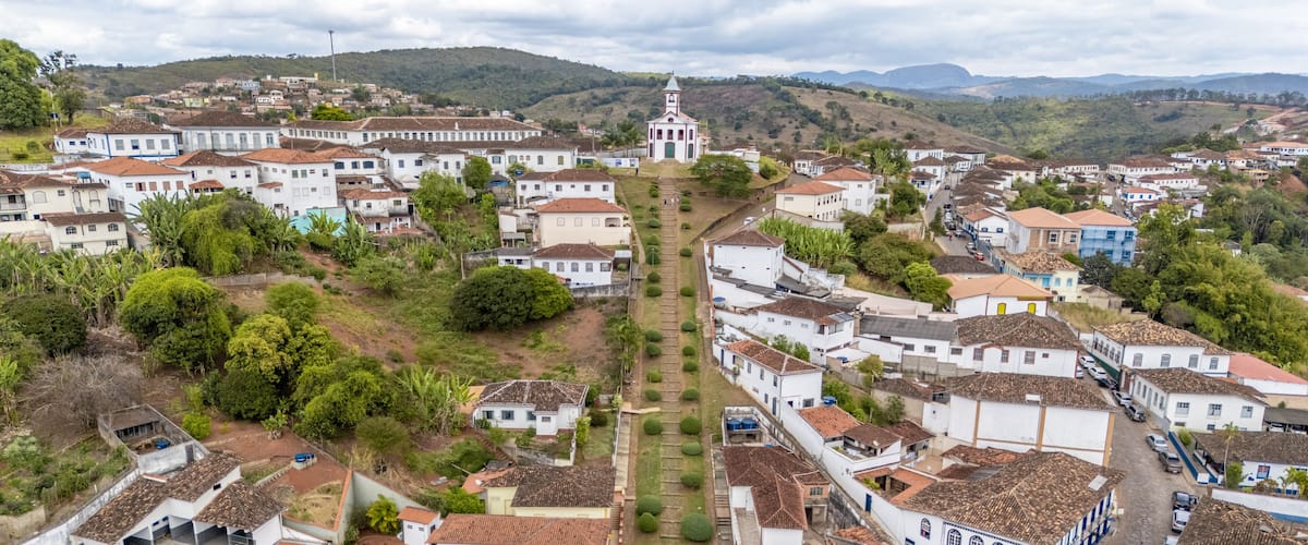 A town with white buildings, a central church, and a hilly landscape in the background.