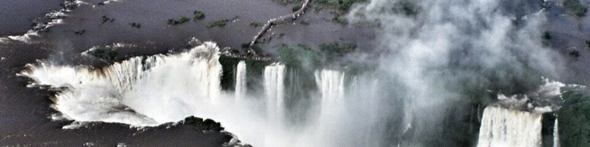 Una cascada vertiéndose en un río rodeado de vegetación.
