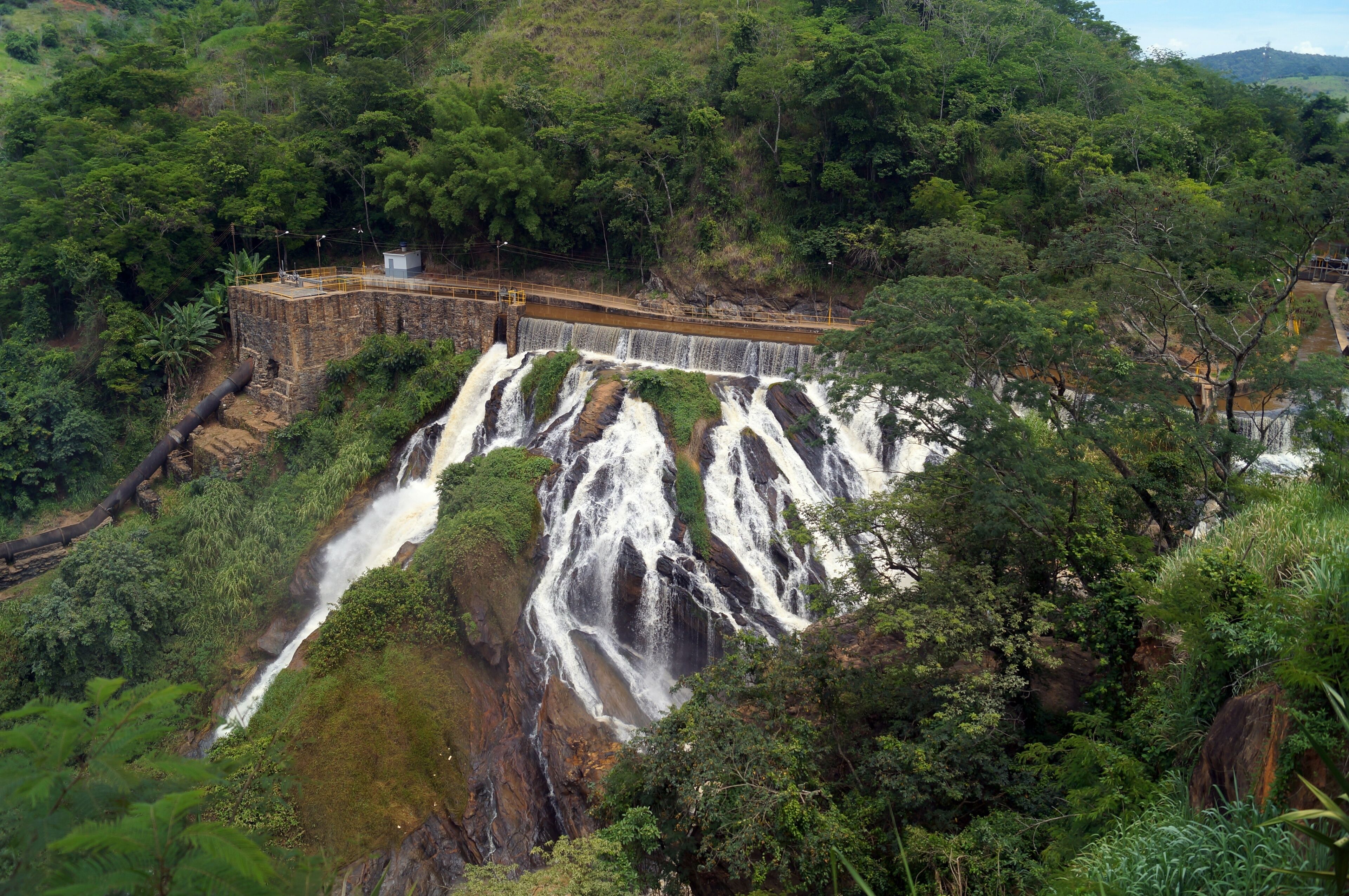 A large waterfall cascading over a rocky cliff surrounded by dense greenery.