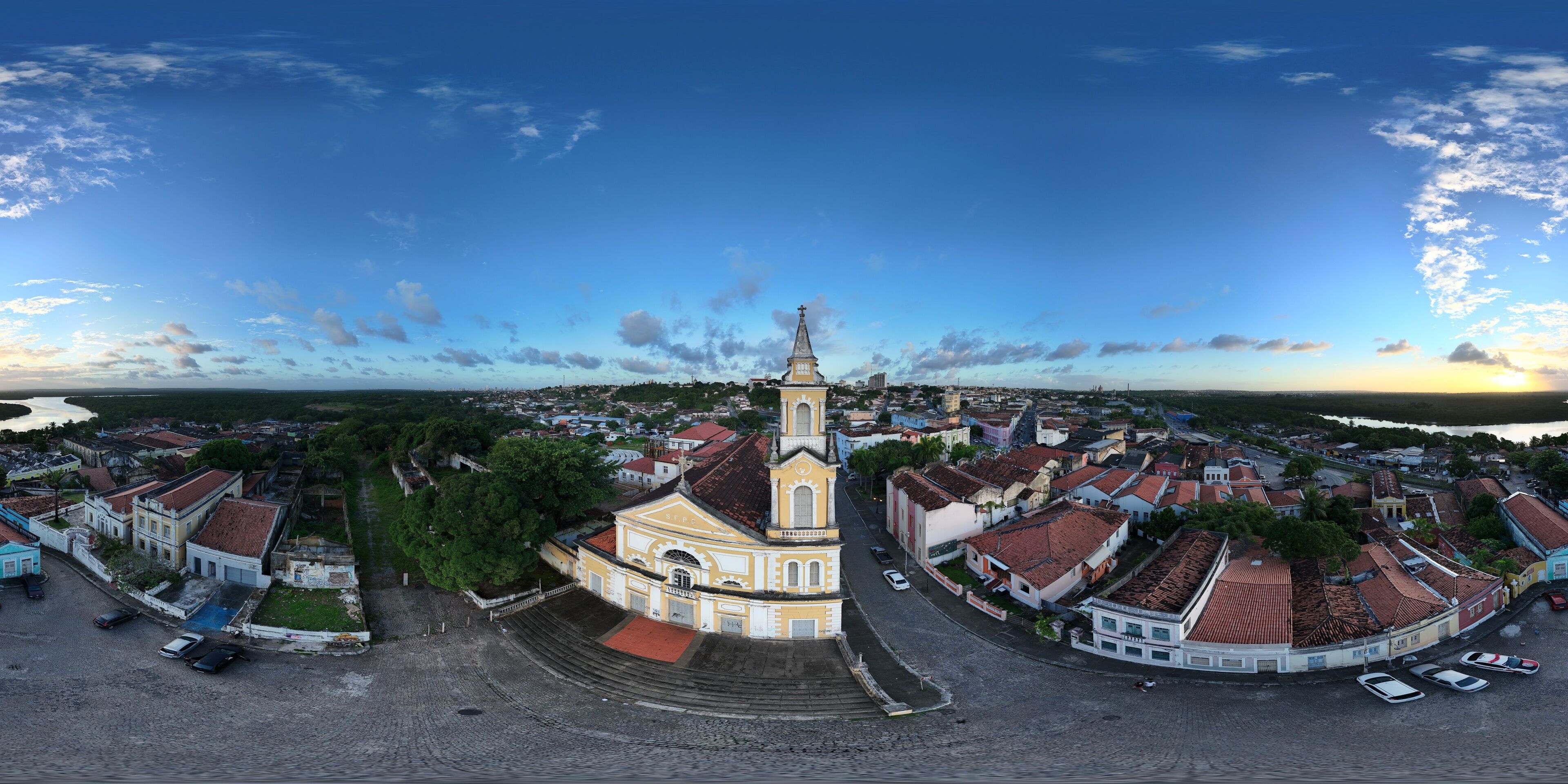 An aerial view of a historic town with a prominent church, cobblestone streets, and a waterfront.