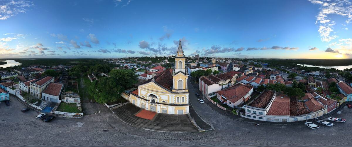An aerial view of a historic town with a prominent church, cobblestone streets, and a waterfront.