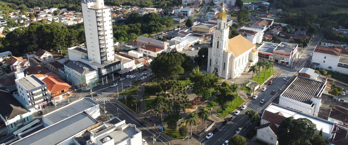 An aerial view of a town with a prominent church, a tall white building, and surrounding residential areas.