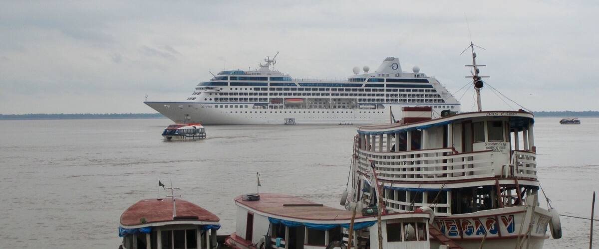 A large cruise ship named 'Sirius' docked at a port with smaller boats nearby.
