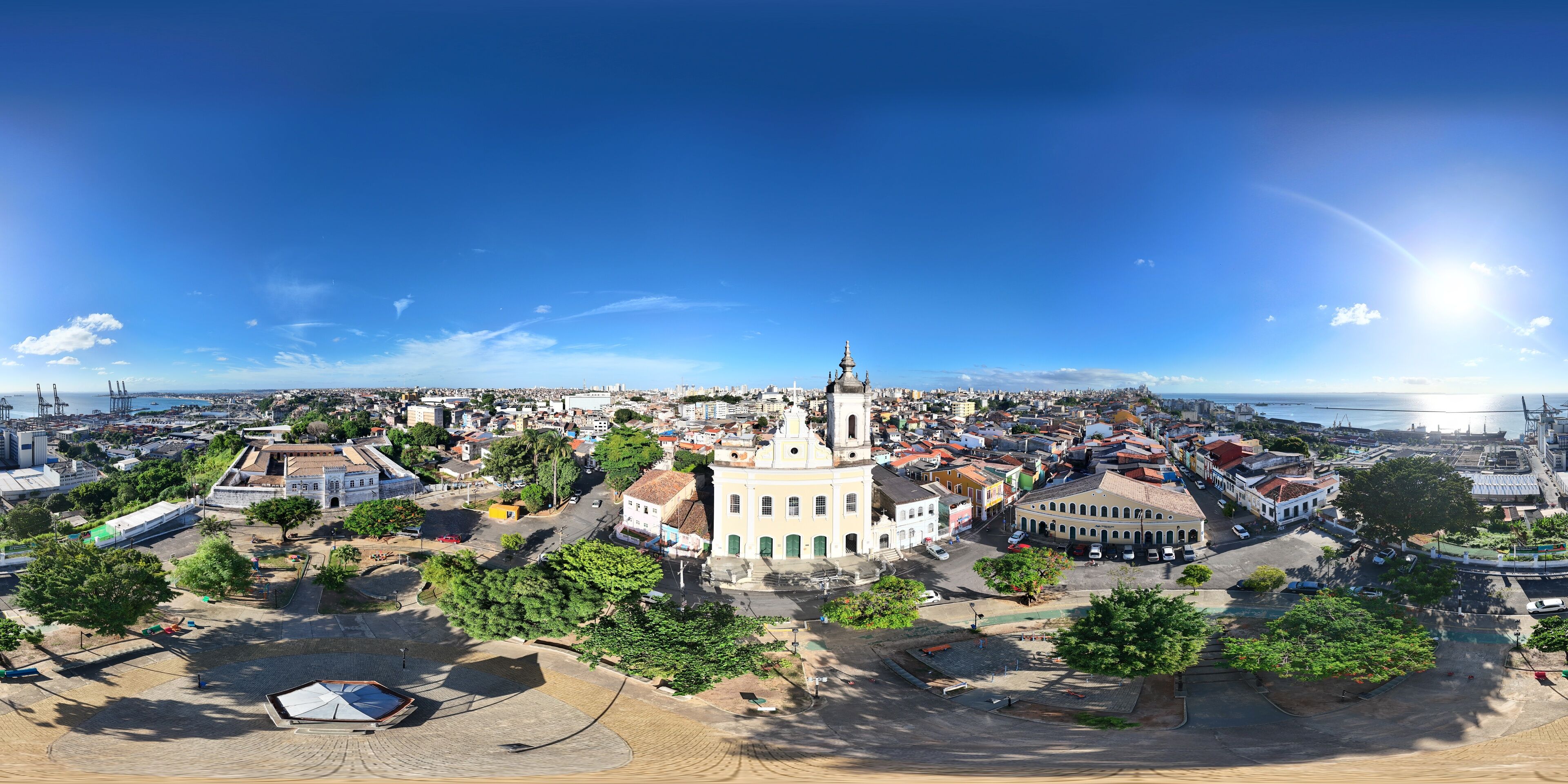 A panoramic view of a coastal city with a prominent church, a harbor, and a mix of historical and modern buildings.