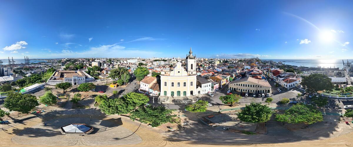 A panoramic view of a coastal city with a prominent church, a harbor, and a mix of historical and modern buildings.