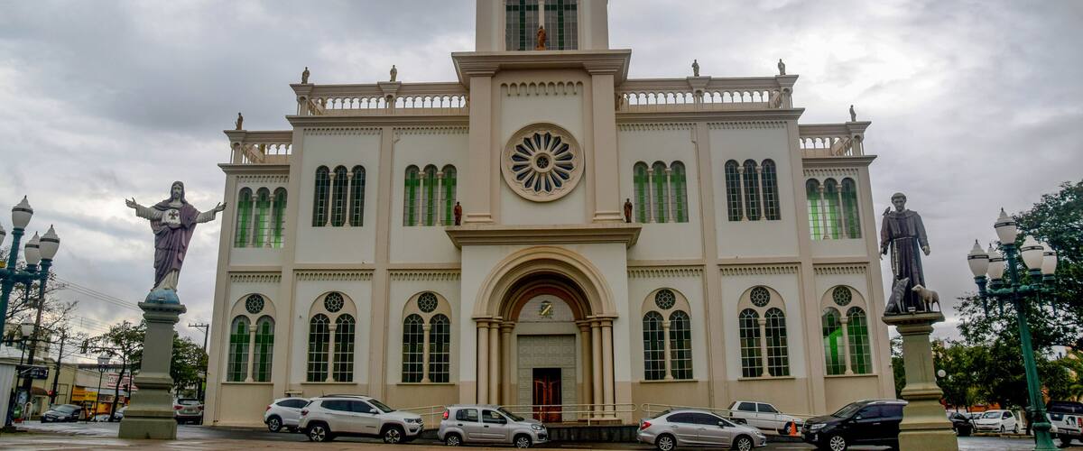 A historic building with a clock tower, statues, and arched windows.