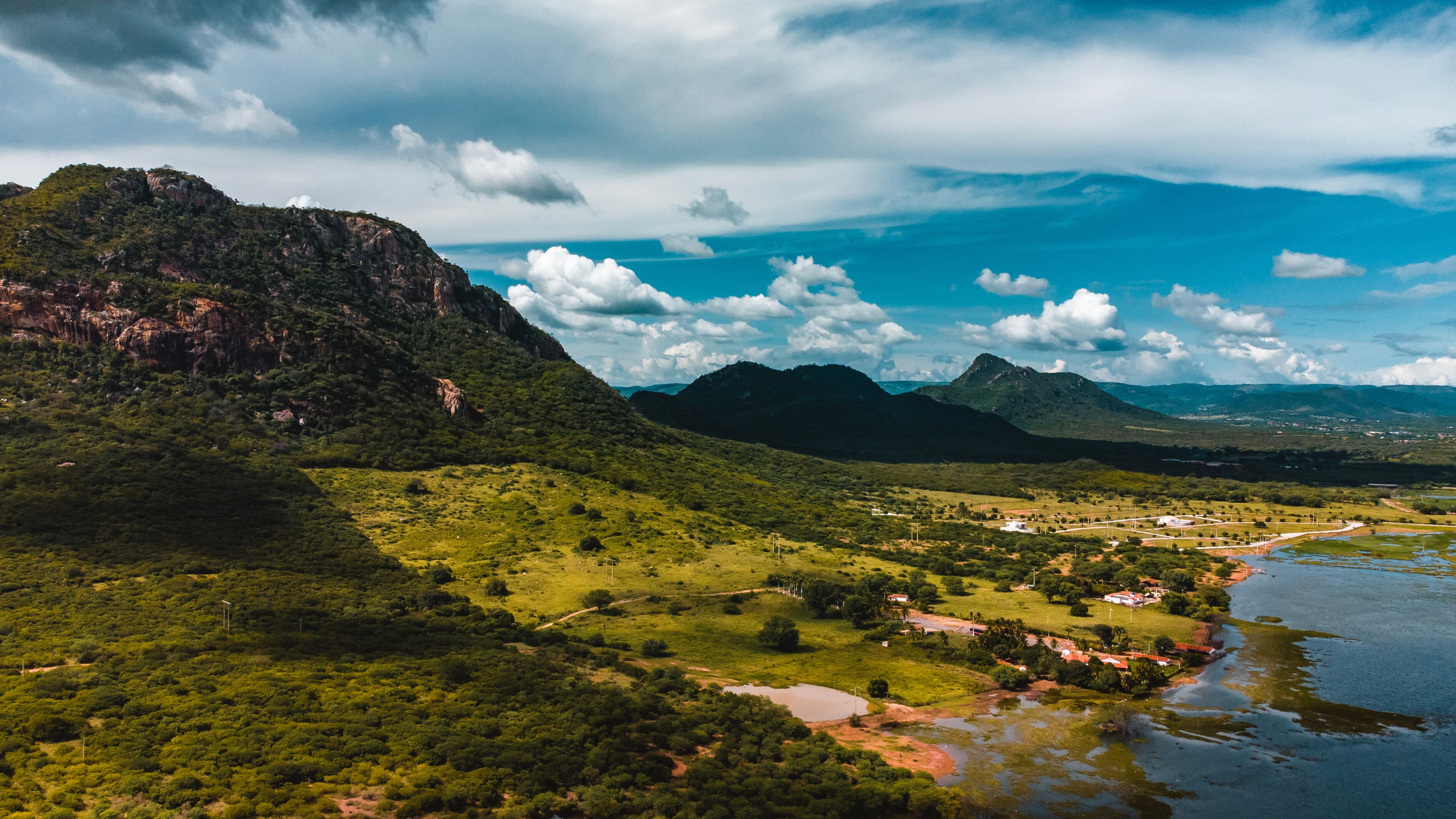 A lush green landscape with a river, mountains, and a small settlement.