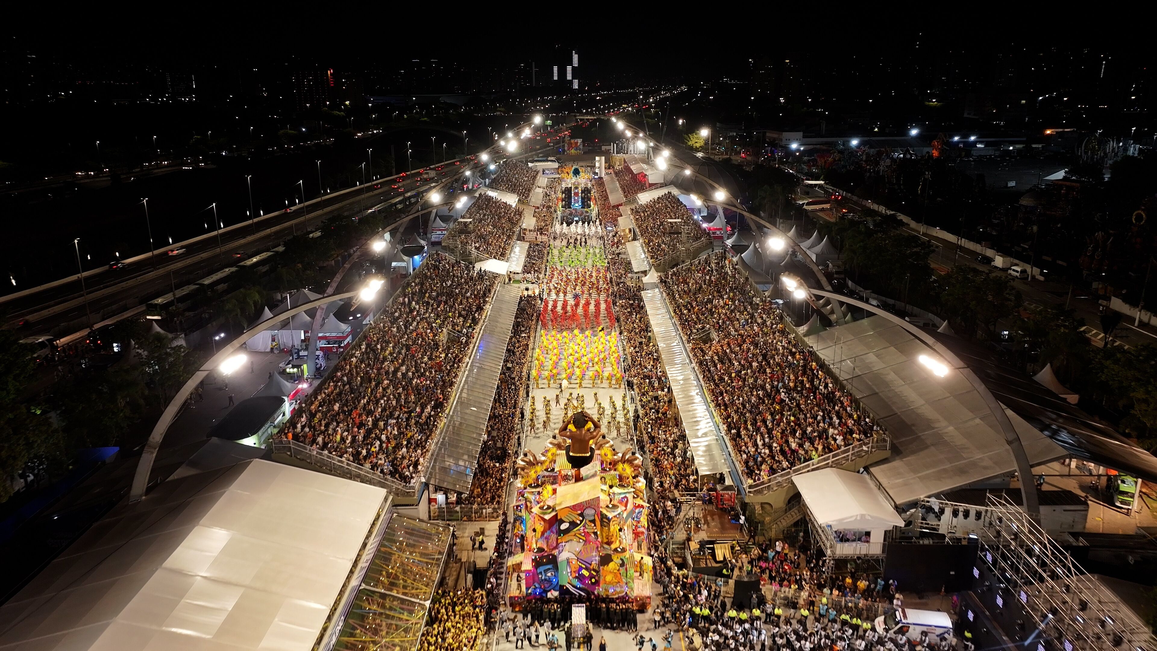 A large outdoor event with a central stage and a crowd.