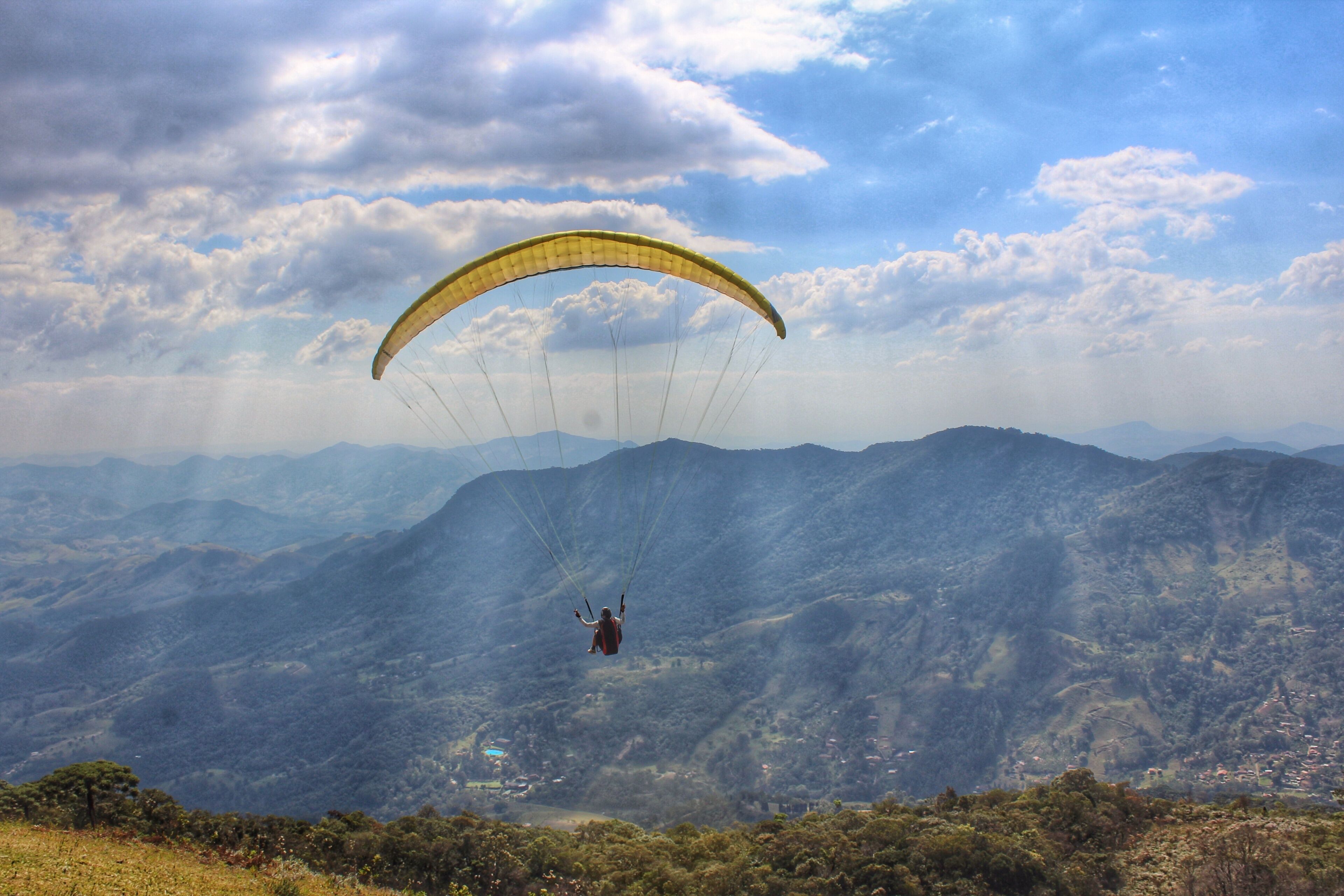 A paraglider over a mountainous landscape with a clear sky.