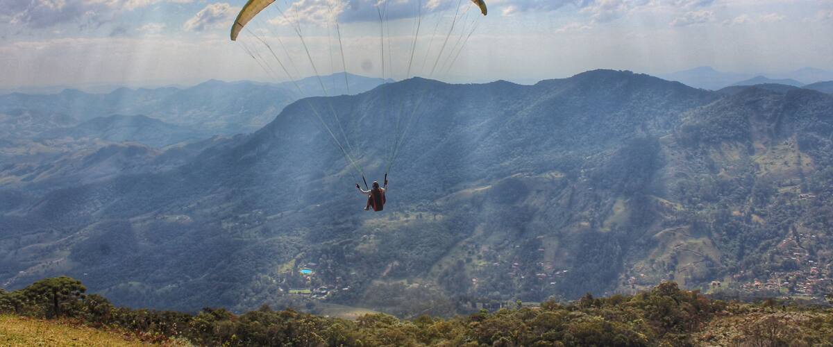 A paraglider over a mountainous landscape with a clear sky.