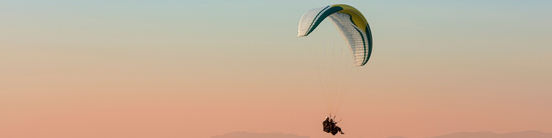 Un parapente volando sobre un paisaje montañoso al atardecer.