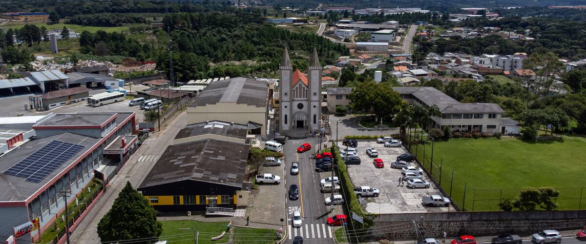 A town with a prominent church, a parking lot, and surrounding greenery.