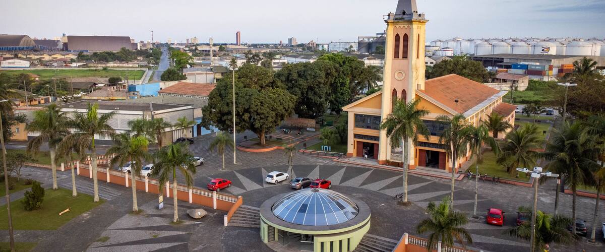 A church with a tall steeple, a round building with a dome, and palm trees.
