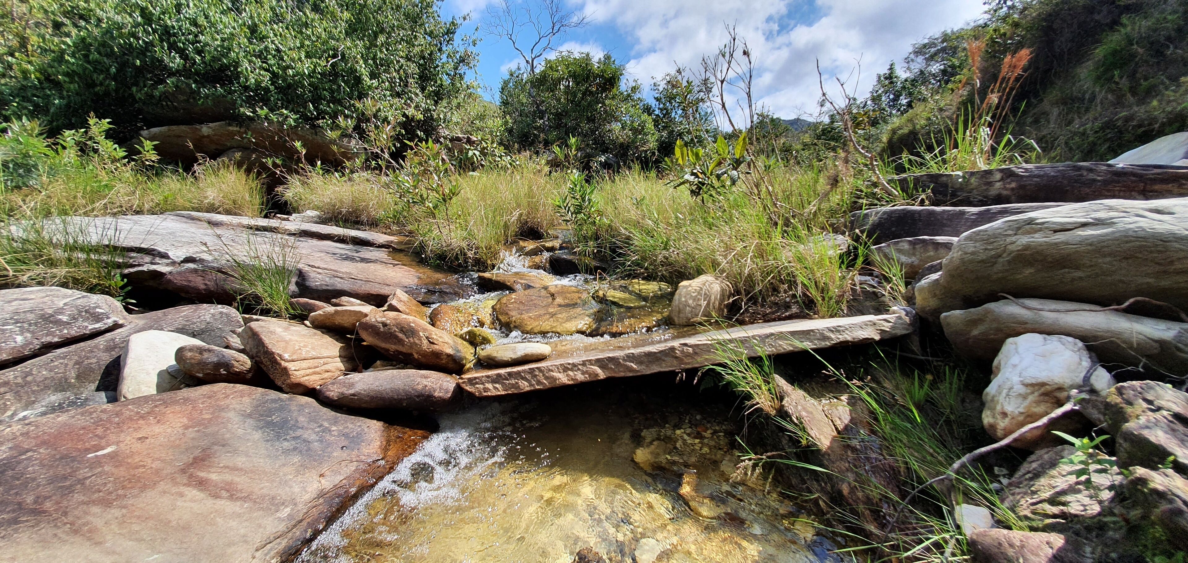 A rocky stream with a wooden bridge.