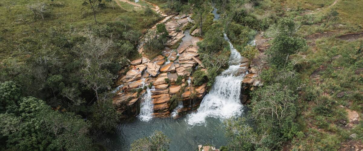 A waterfall cascading over rocky terrain surrounded by dense greenery.