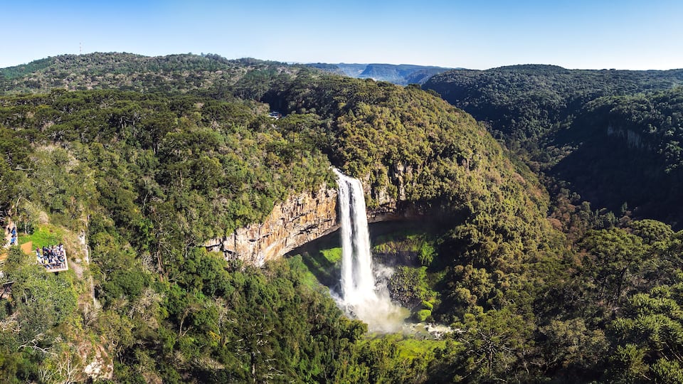 Une cascade d’eau se déversant sur une montagne verdoyante et couverte de forêts.