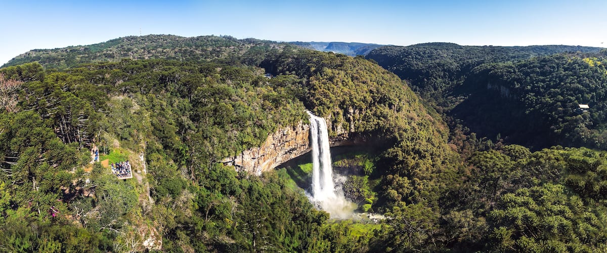 A waterfall cascading down a lush, forested mountain.