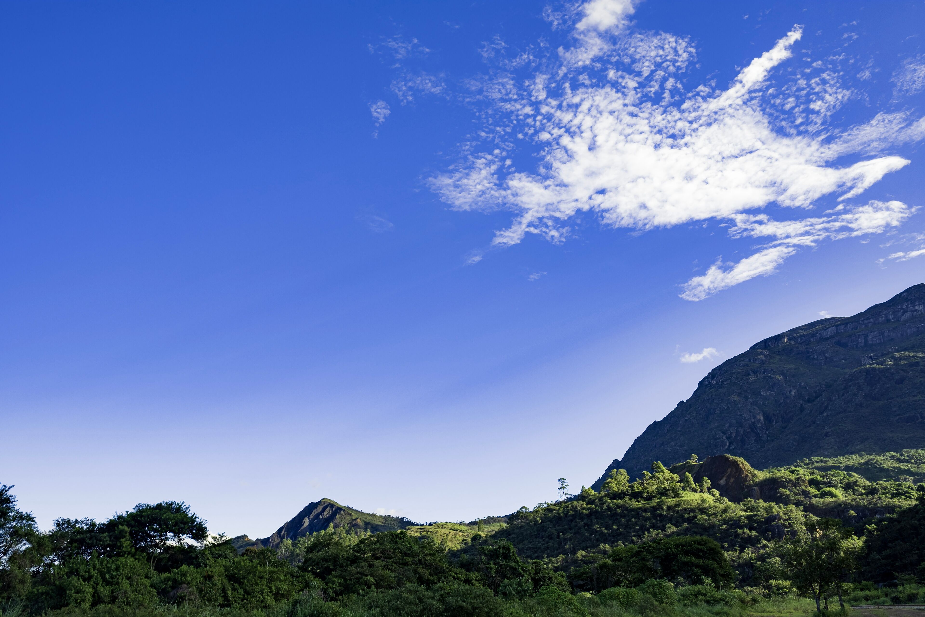 A mountainous landscape with lush greenery and a clear blue sky.