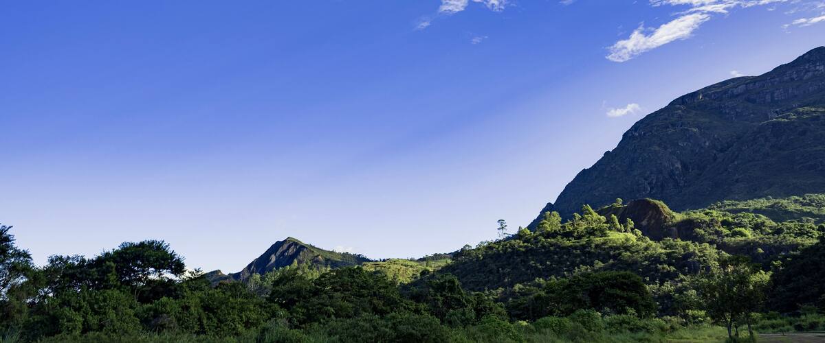 A mountainous landscape with lush greenery and a clear blue sky.