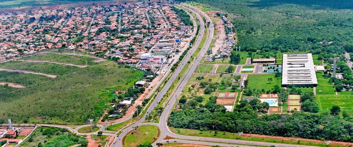 An aerial view of a city with a highway curving through it, surrounded by residential areas and green spaces.