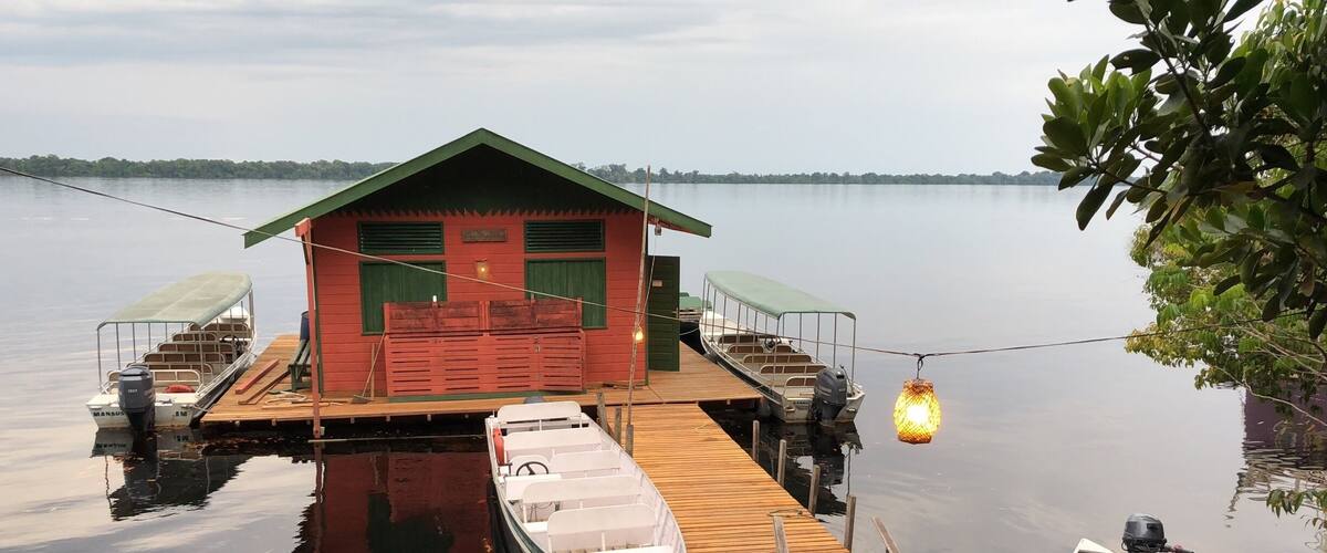 A wooden dock with a red house and two boats.