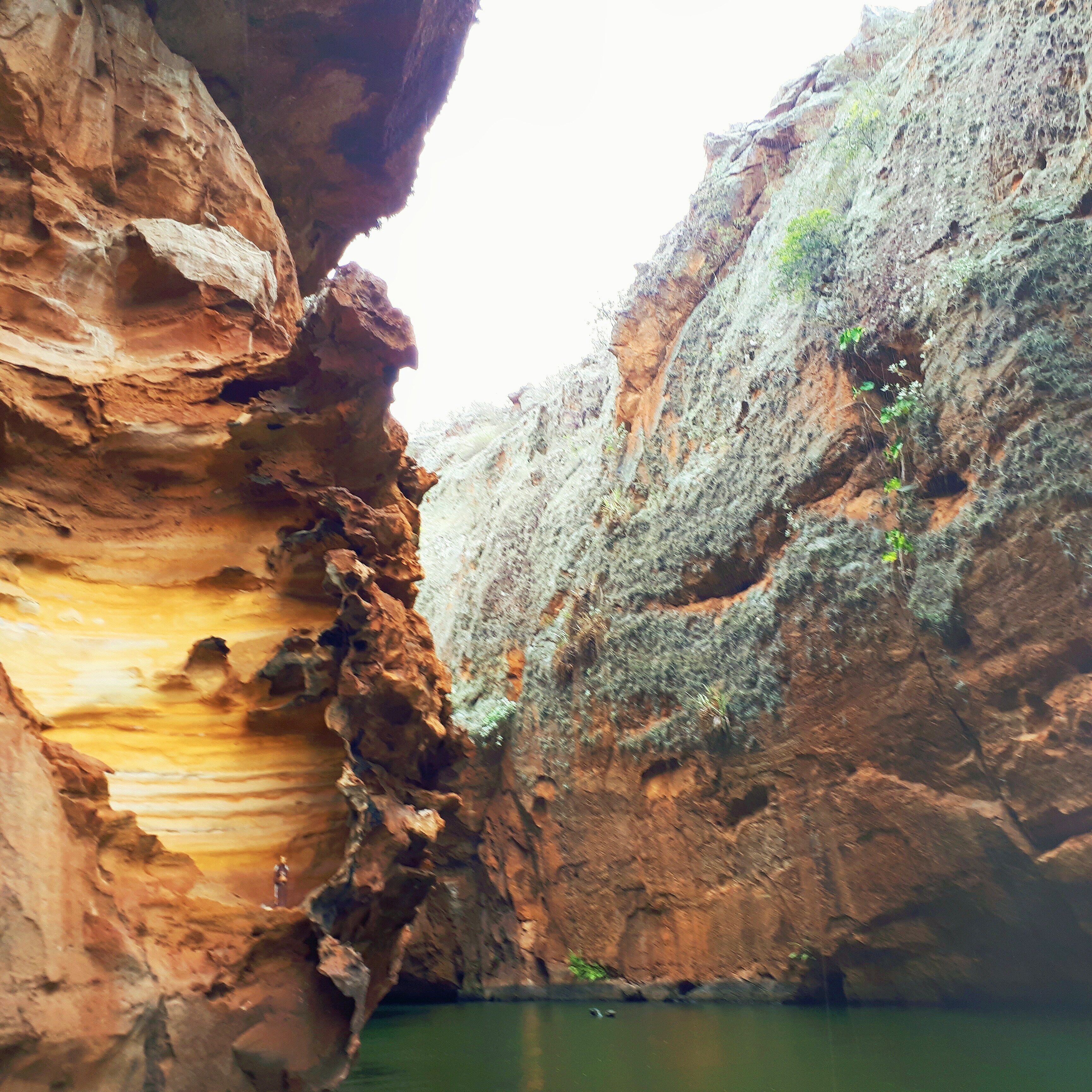 A canyon with steep rock walls and a narrow water channel.