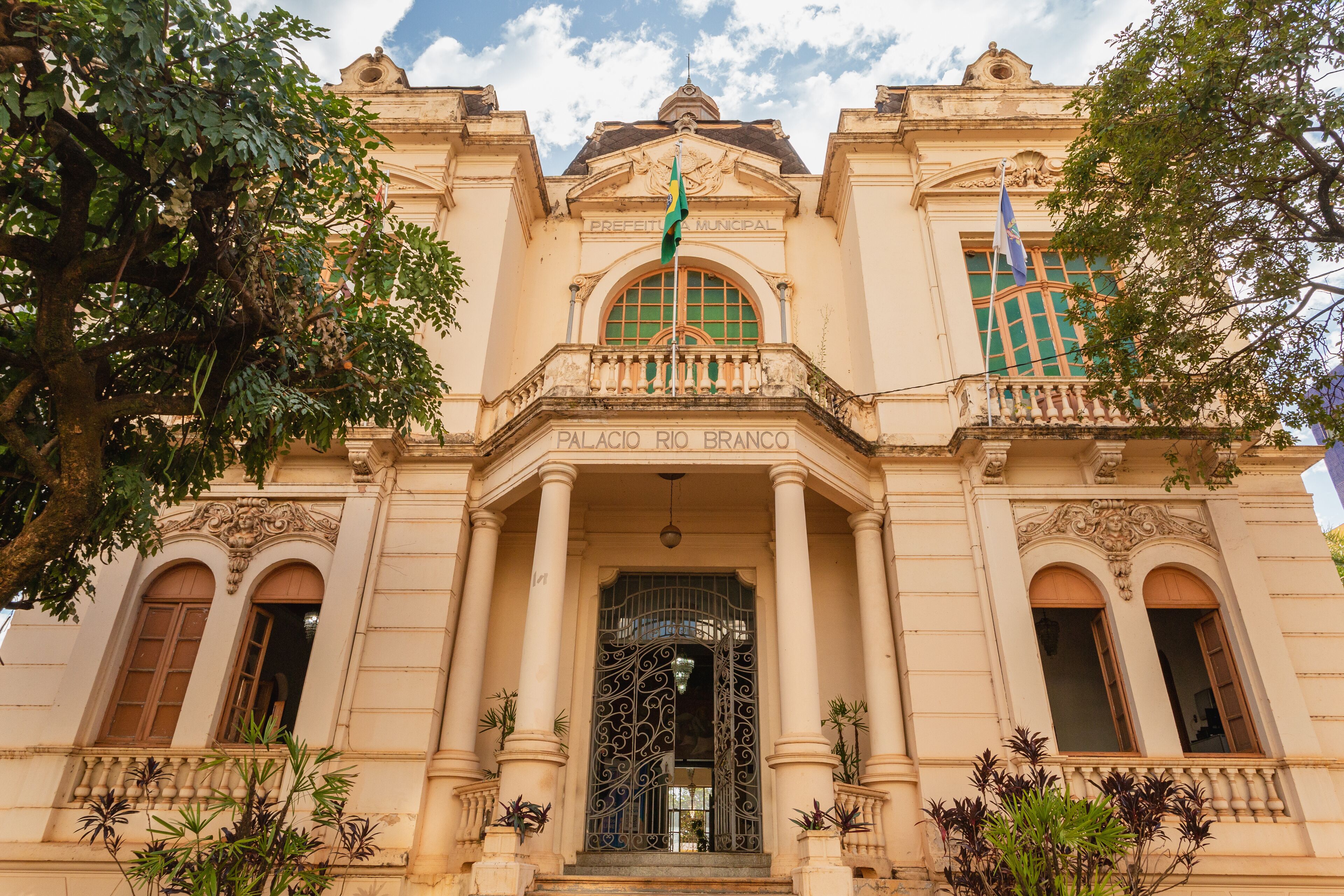 A historic building with ornate architecture, including columns, a balcony, and a large arched window.