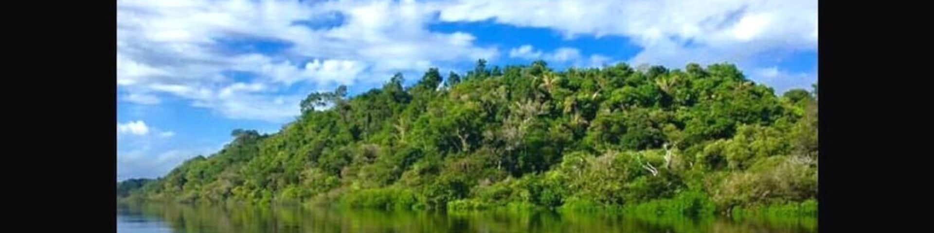 A calm river reflecting the sky and a lush green hill.