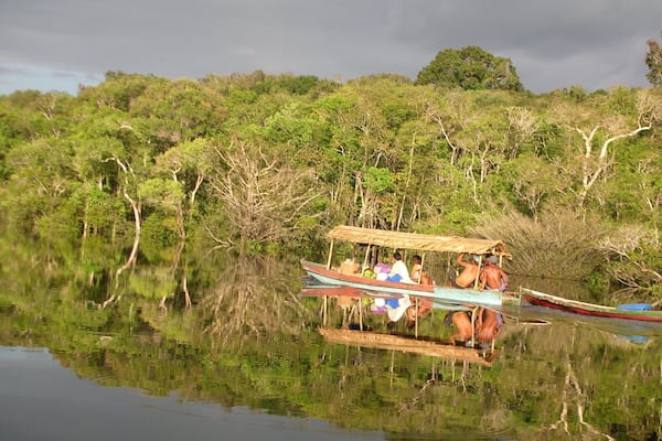 A boat on a calm river surrounded by dense green foliage.