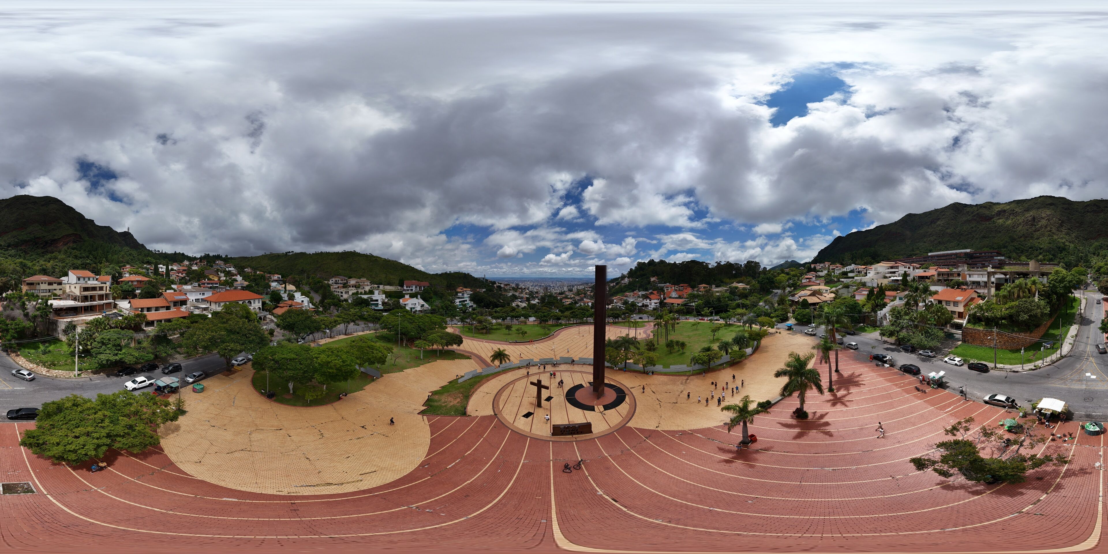 A large stadium with a running track, surrounded by a park with palm trees and a cityscape in the background.