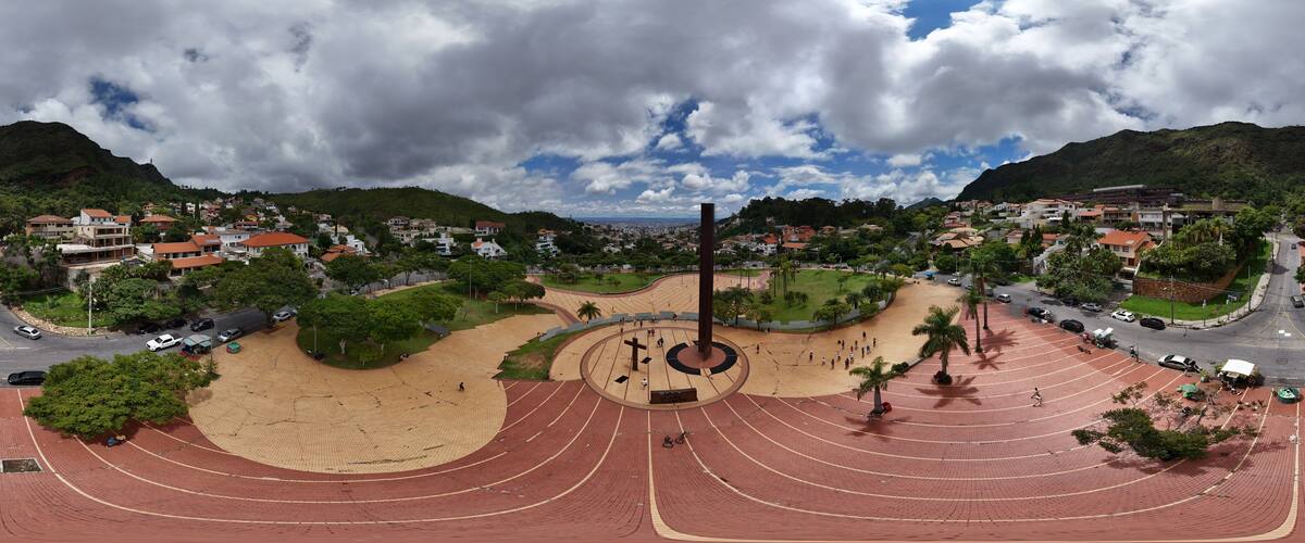 A large stadium with a running track, surrounded by a park with palm trees and a cityscape in the background.
