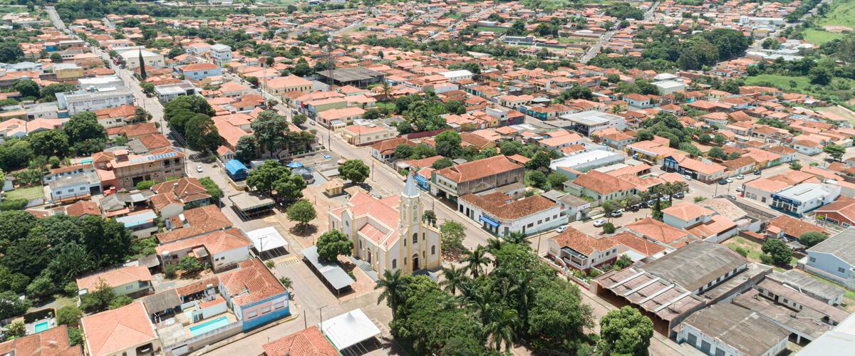 A densely populated urban area with red-roofed buildings, a prominent church, and surrounding greenery.
