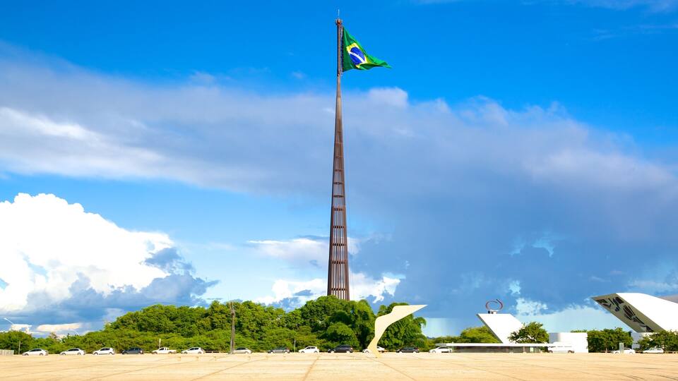 A tall tower with a flag, surrounded by trees and modern architecture.