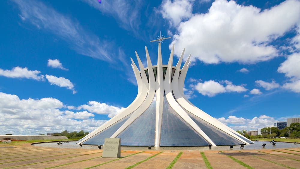 A modern architectural structure with a star-like top, surrounded by a reflective water body and a clear blue sky.