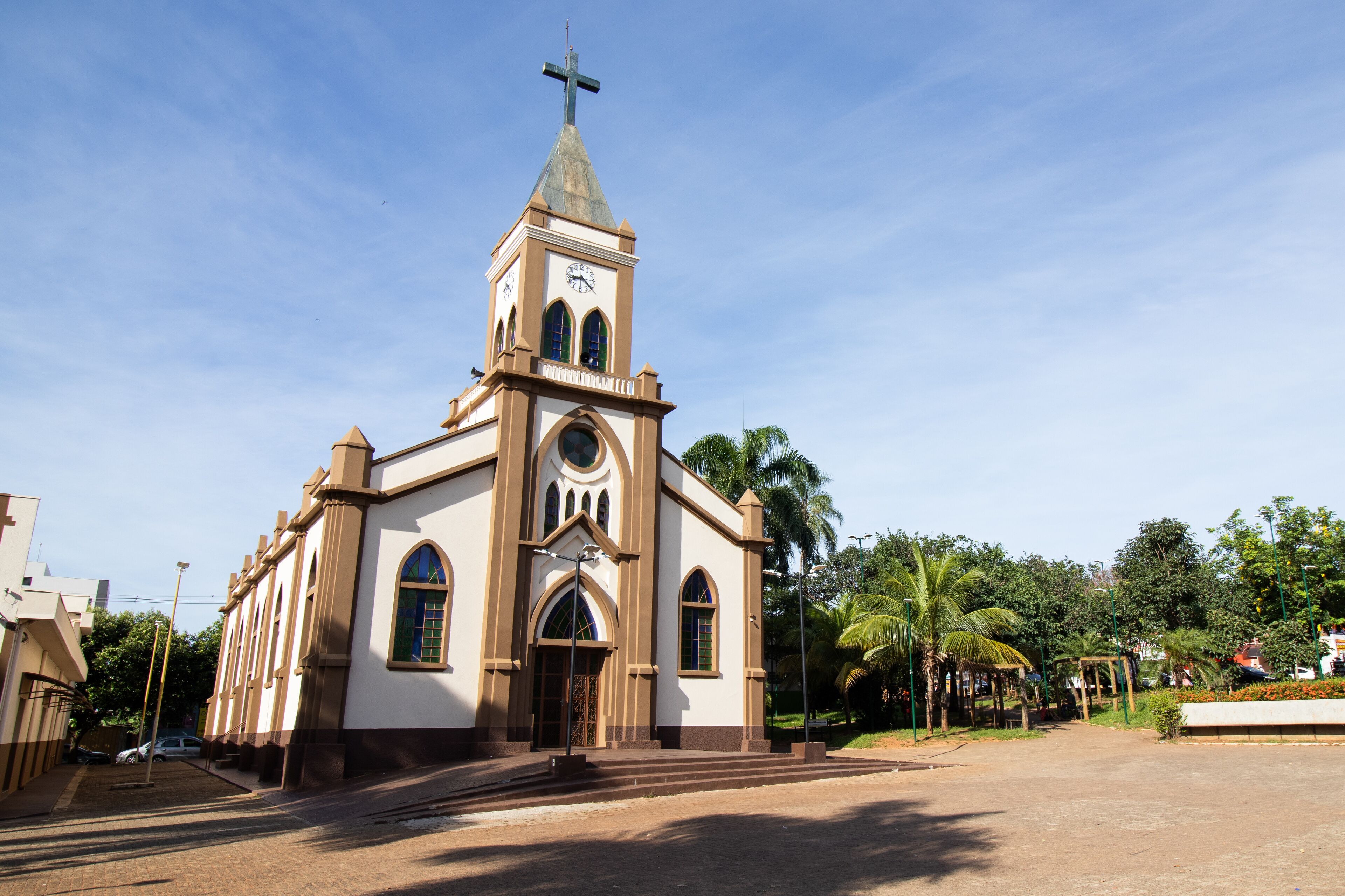 A church with a cross on top, arched windows, and a clock.