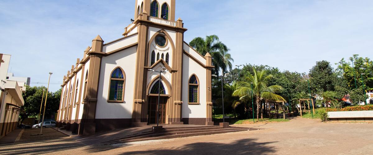 A church with a cross on top, arched windows, and a clock.