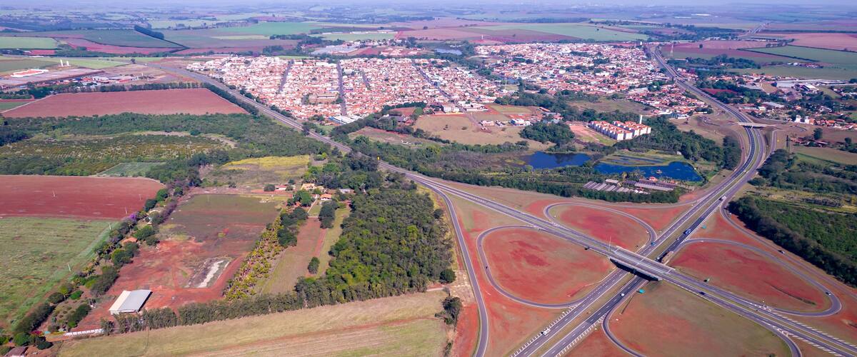 An aerial view of a town with a complex highway interchange surrounded by agricultural fields and a large residential area.