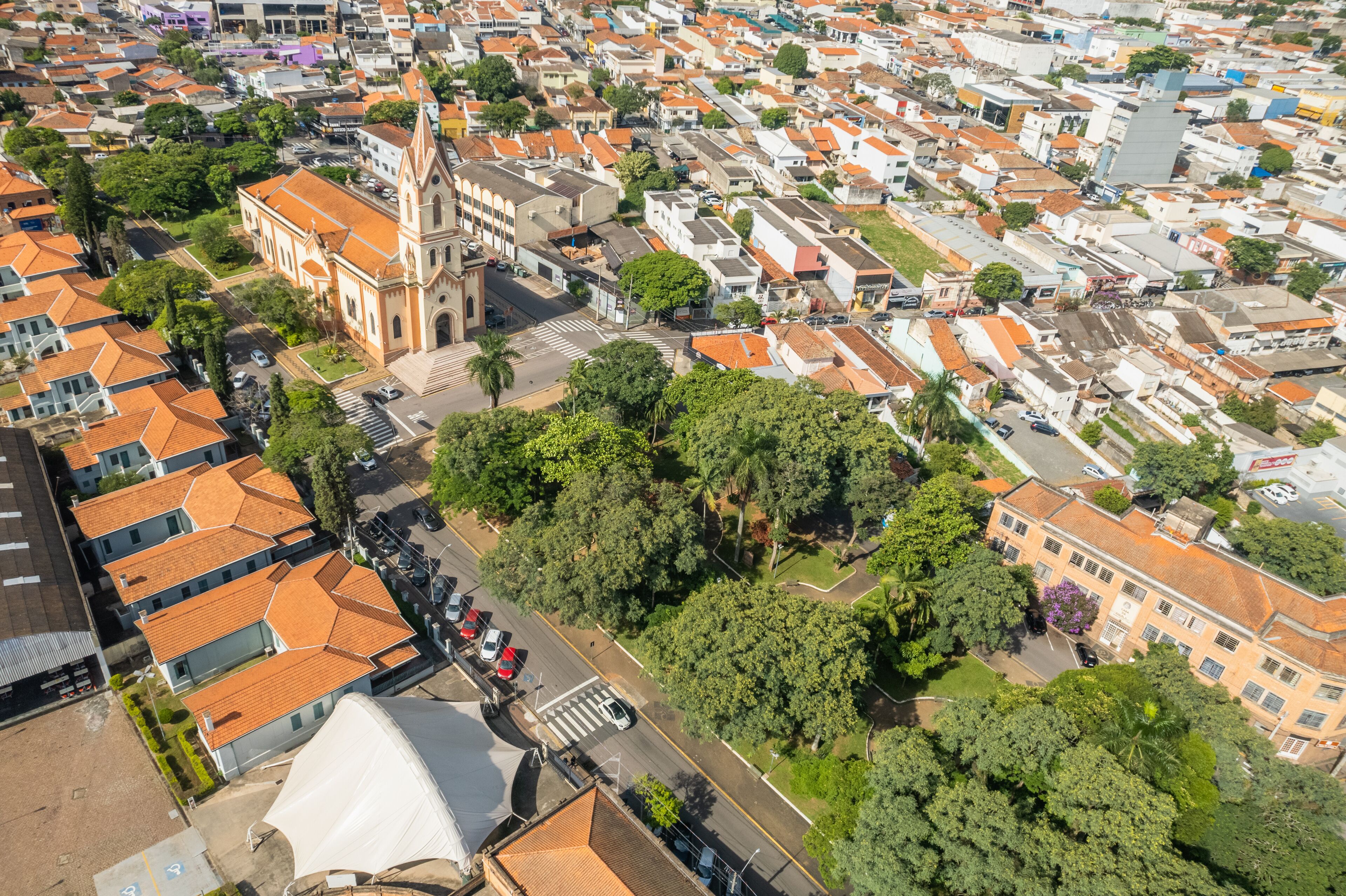 An aerial view of a densely packed urban area with a prominent church, numerous residential buildings, and lush green trees.