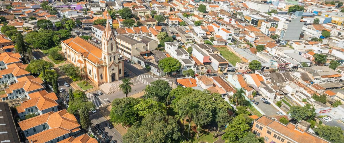 An aerial view of a densely packed urban area with a prominent church, numerous residential buildings, and lush green trees.