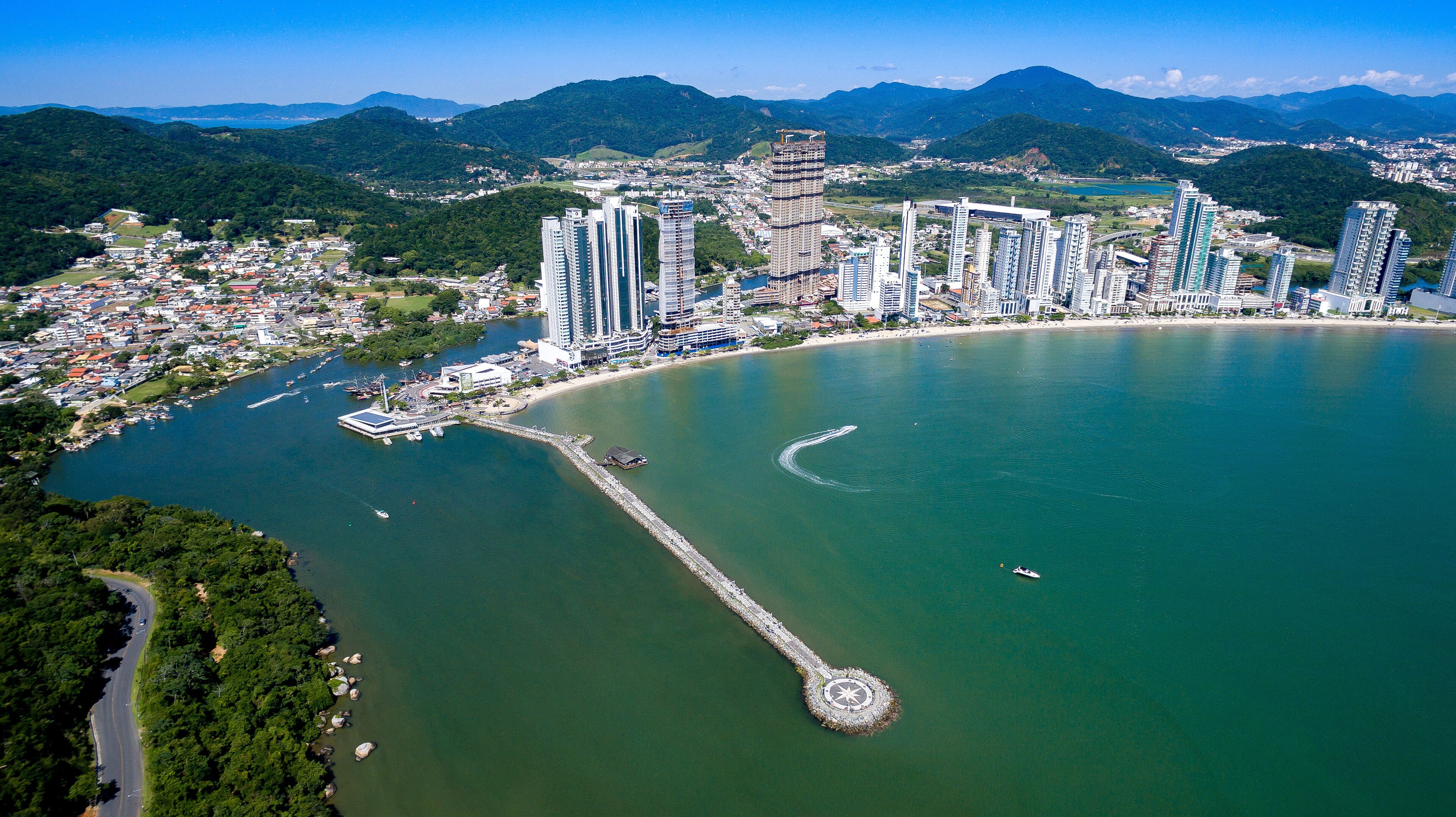 A coastal city with high-rise buildings, a marina, and a lighthouse.
