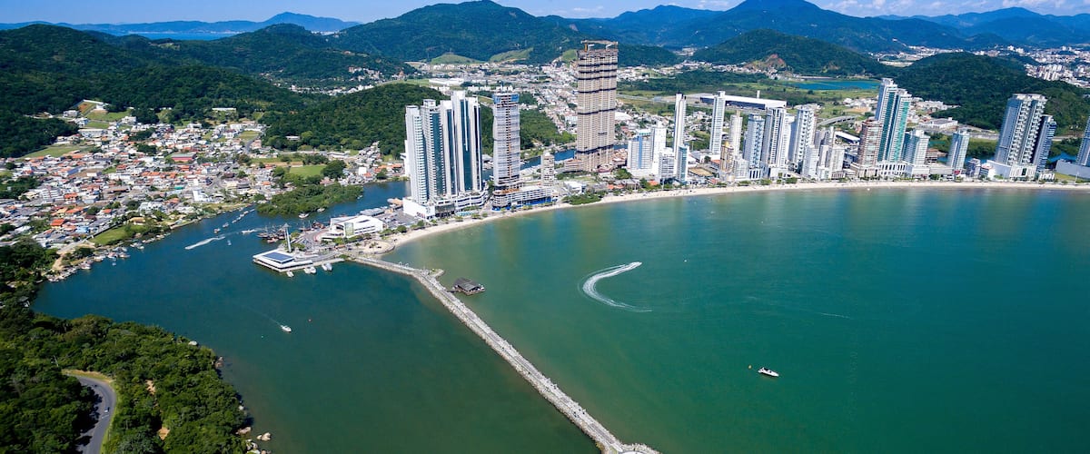 A coastal city with high-rise buildings, a marina, and a lighthouse.