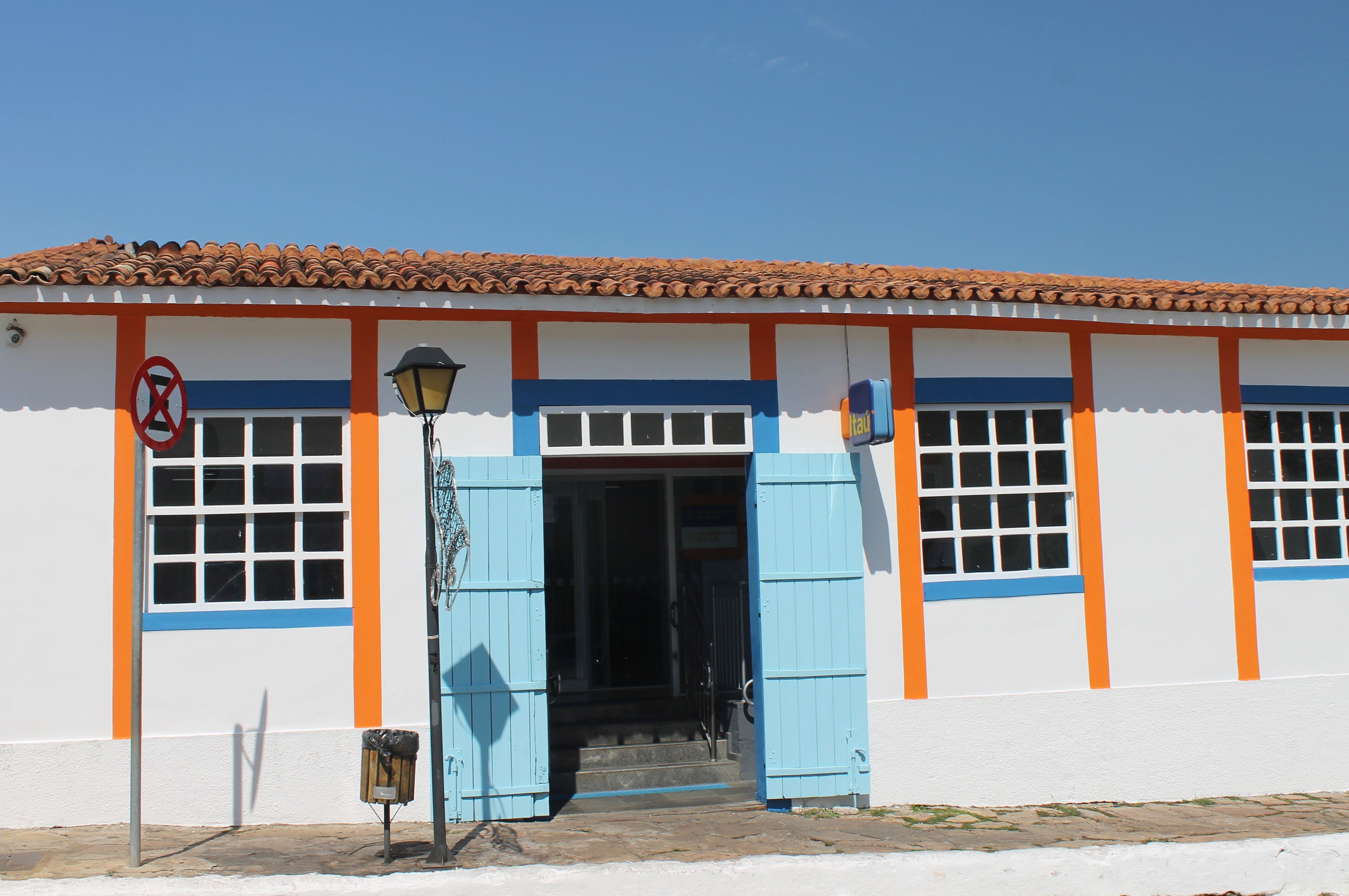 A building with a tiled roof, blue shutters, and a no parking sign.