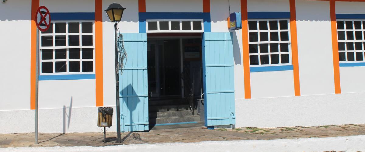 A building with a tiled roof, blue shutters, and a no parking sign.