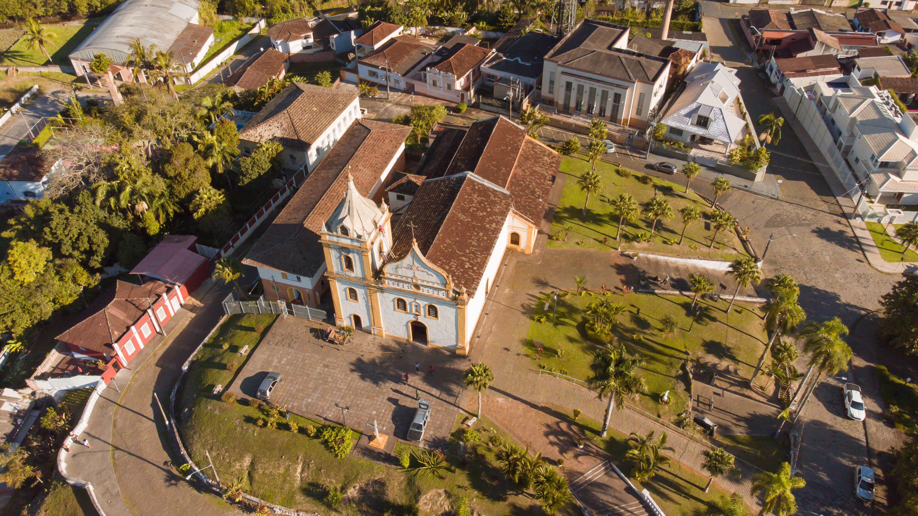 An aerial view of a town with a prominent church, palm trees, and residential buildings.