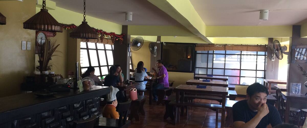 A restaurant interior with wooden tables, chairs, and a bar area.