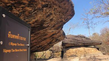 A large rock shelter with a sign in front.