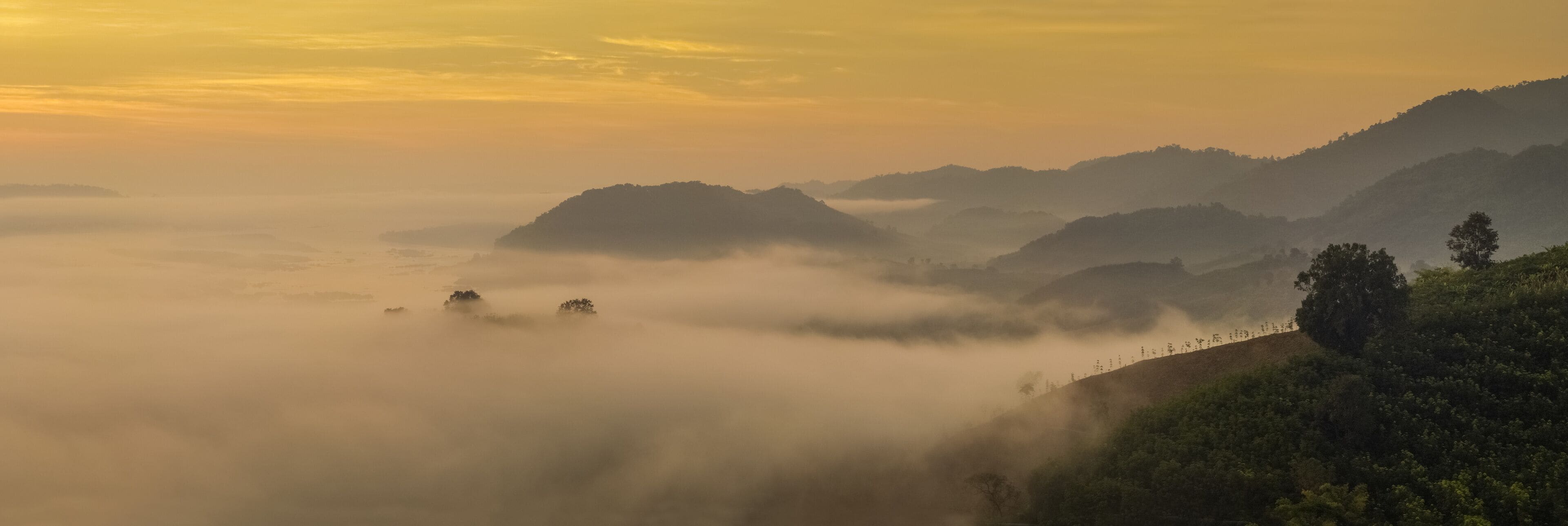 sunrise at Phu Huay E San View Point, view of the hill around with sea of mist above Mekong river with yellow sun light in the sky background, Ban Muang, Sang Khom District, Nong Khai, Thailand.